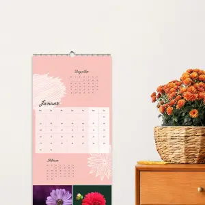 3-Monatskalender als Wandkalender 2025 an einer Wand und ein Sideboard mit Blumen